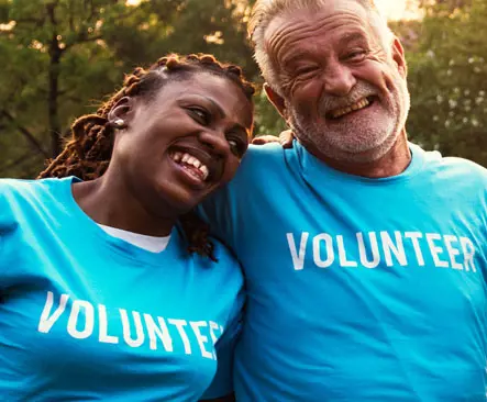 Two people in volunteer shirts hugging