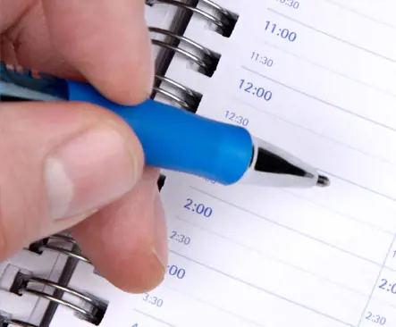 Hand holding a pen writing in an appointment book