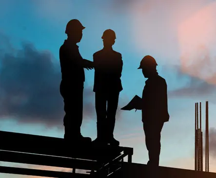 Three construction workers in hard hats standing on a site