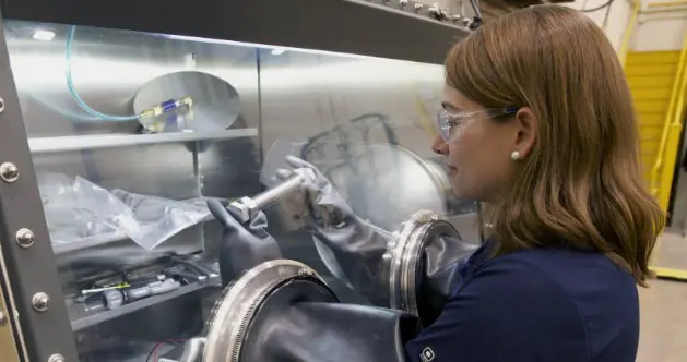 Woman in safety glasses using safety gloves to handle material
