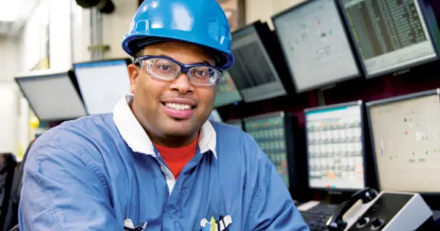 Man in hard hat sitting in front of computer screens