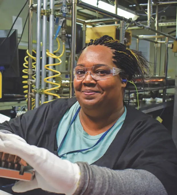 Woman wearing safety glasses in front of a machine